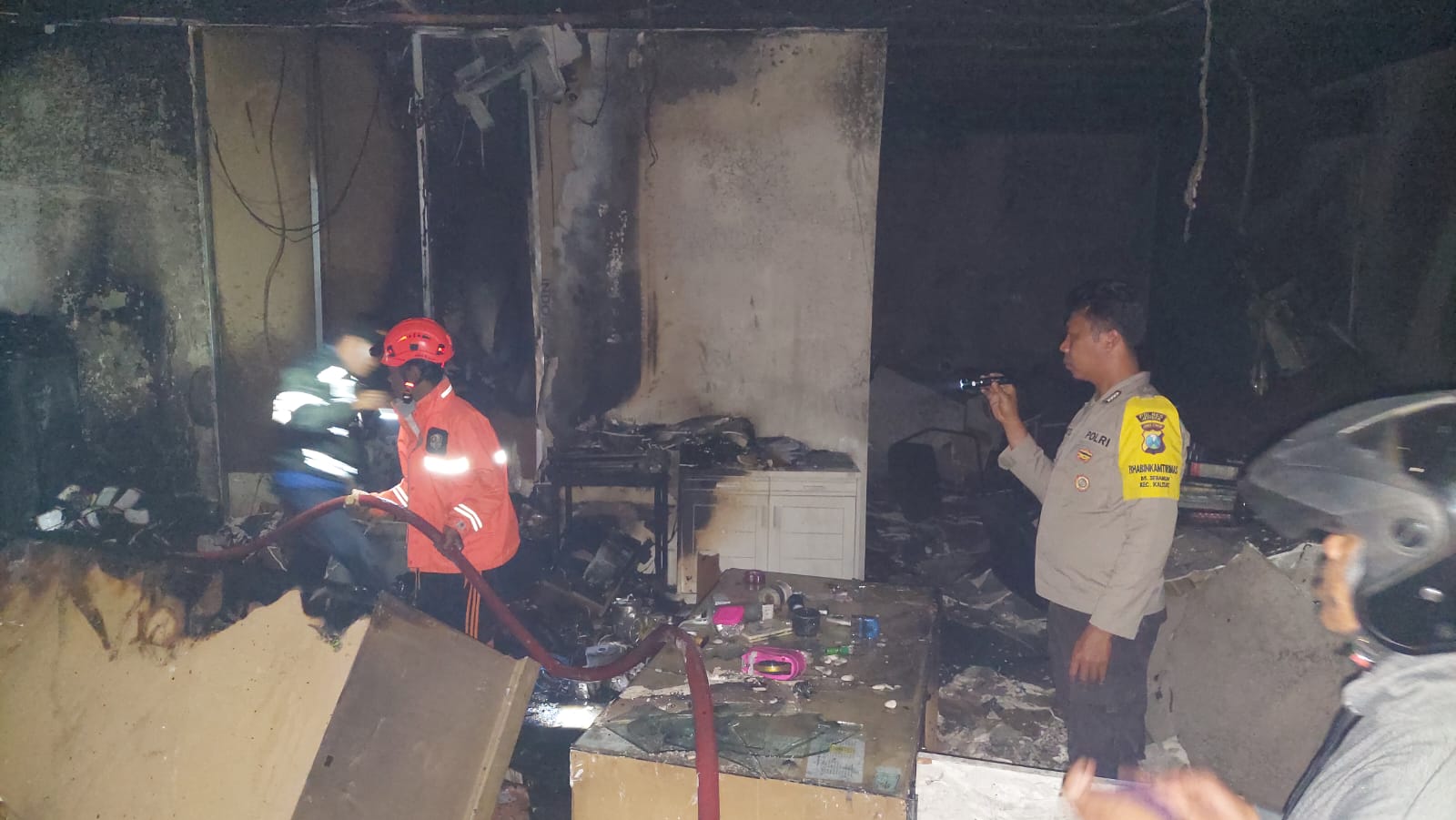 DATANGI LOKASI: Kapolsek Kalisat Iptu Ika Mufid Dati bersama anggotanya memasang police line di lokasi terbakarnya Kantor Bank Jatim Pembantu Kalisat, Selasa (29/4) dini hari. (POLSEK KALISAT/RJ)