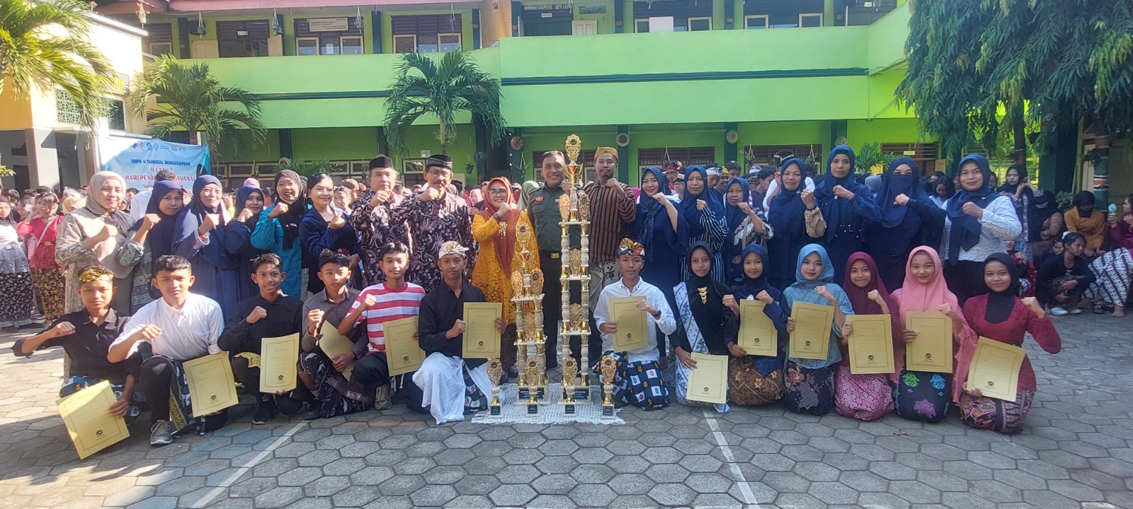 TINGKAT NASIONAL: Kepala SMPN 4 Tanggul Hermin Agustin, ketua komite sekolah, pelatih, dan orang tua siswa saat foto bersama dengan trofi kejuaraan Pencak Silat Championship Tingkat Nasional tahun
