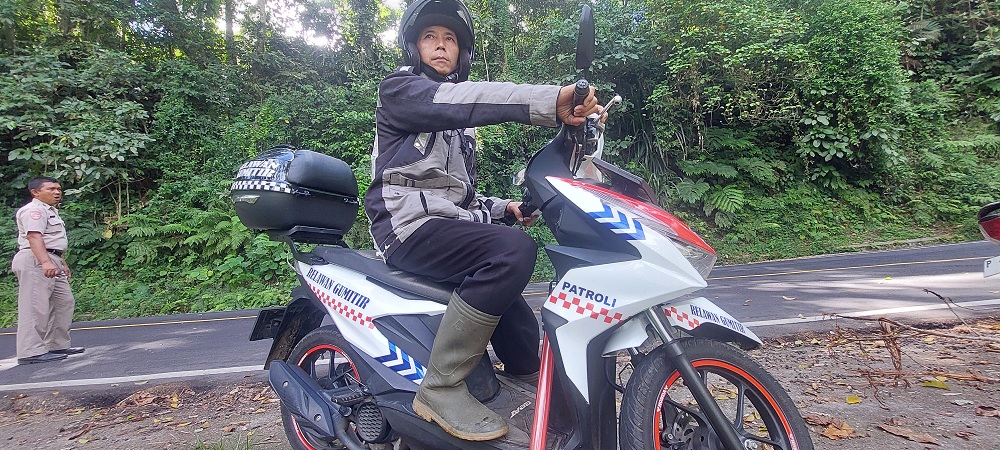 MENGABDI: Wiji Hariyanto dengan sepeda motornya di Jalur Gumitir, kemarin. (JUMAI/RADAR JEMBER)
