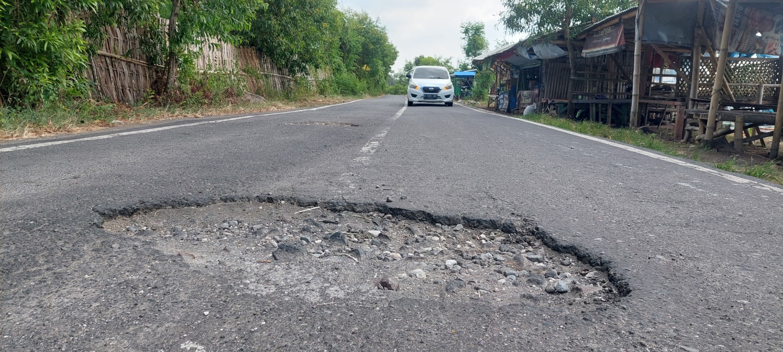 RAWAN KECELAKAAN: Lubang ditengah jalan disekitar jembatan menuju Pancer Puger Desa Puger Kulon, kecamatan Puger yang sering makan korban yakni kecelakaan. (JUMAI/RJ)