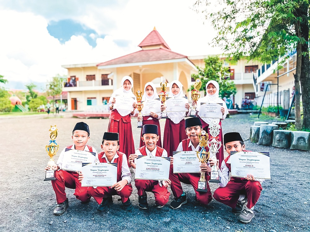 CERDAS DAN TANGKAS: Sembilan siswa MI Unggulan Nuris foto bersama seusai menang Porseni dan menerima piala dari Kemenag Jember, April lalu. (Nuris Jember)