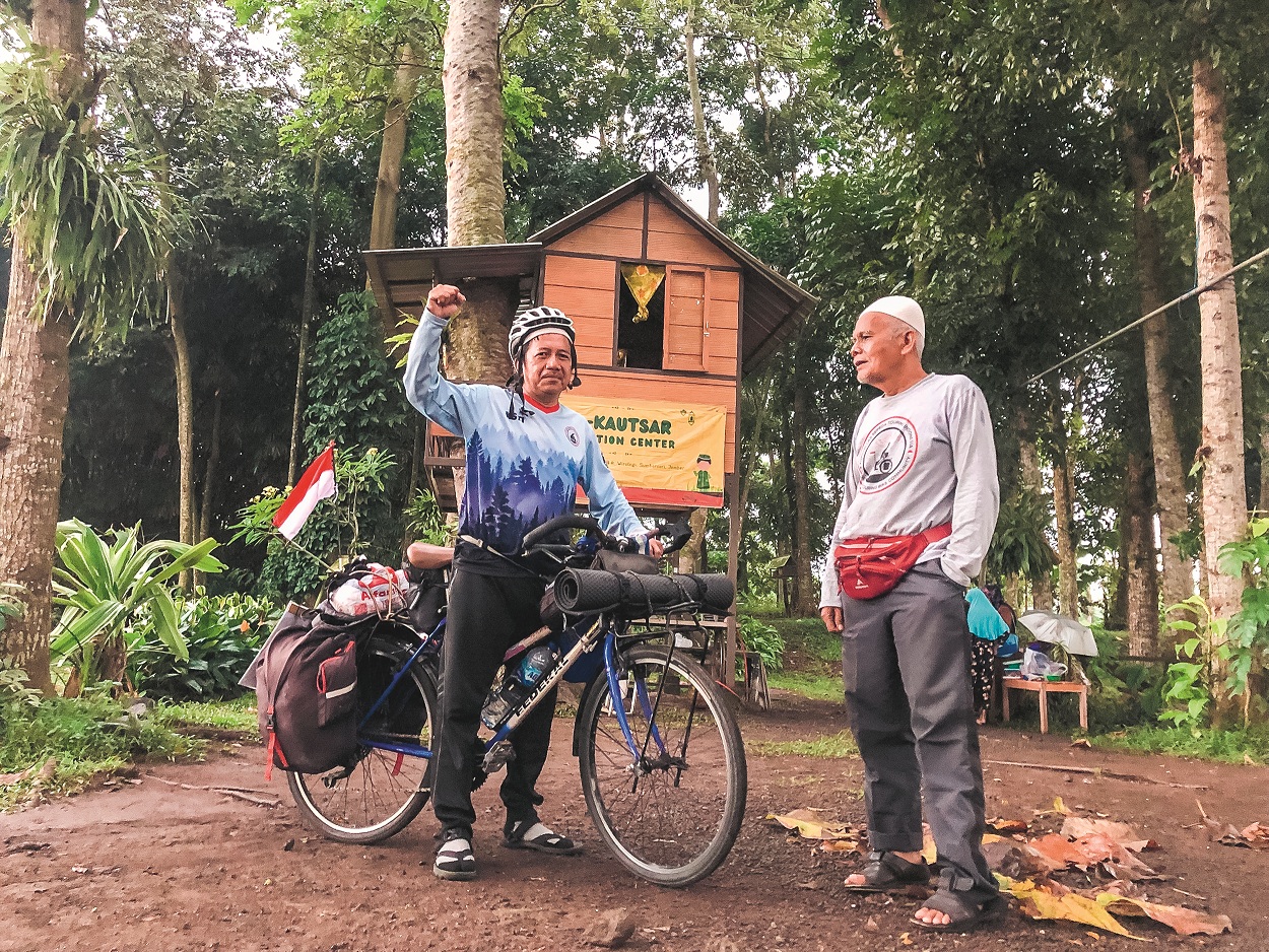 Pesepeda asal Jawa Barat, Taufik Abriansyah (kiri), berbincang dengan Masduki Dumehno, di rumah singgah di Jember, sebelum melanjutkan perjalanan menuju Merauke. (YULIO FA/RADAR JEMBER)
