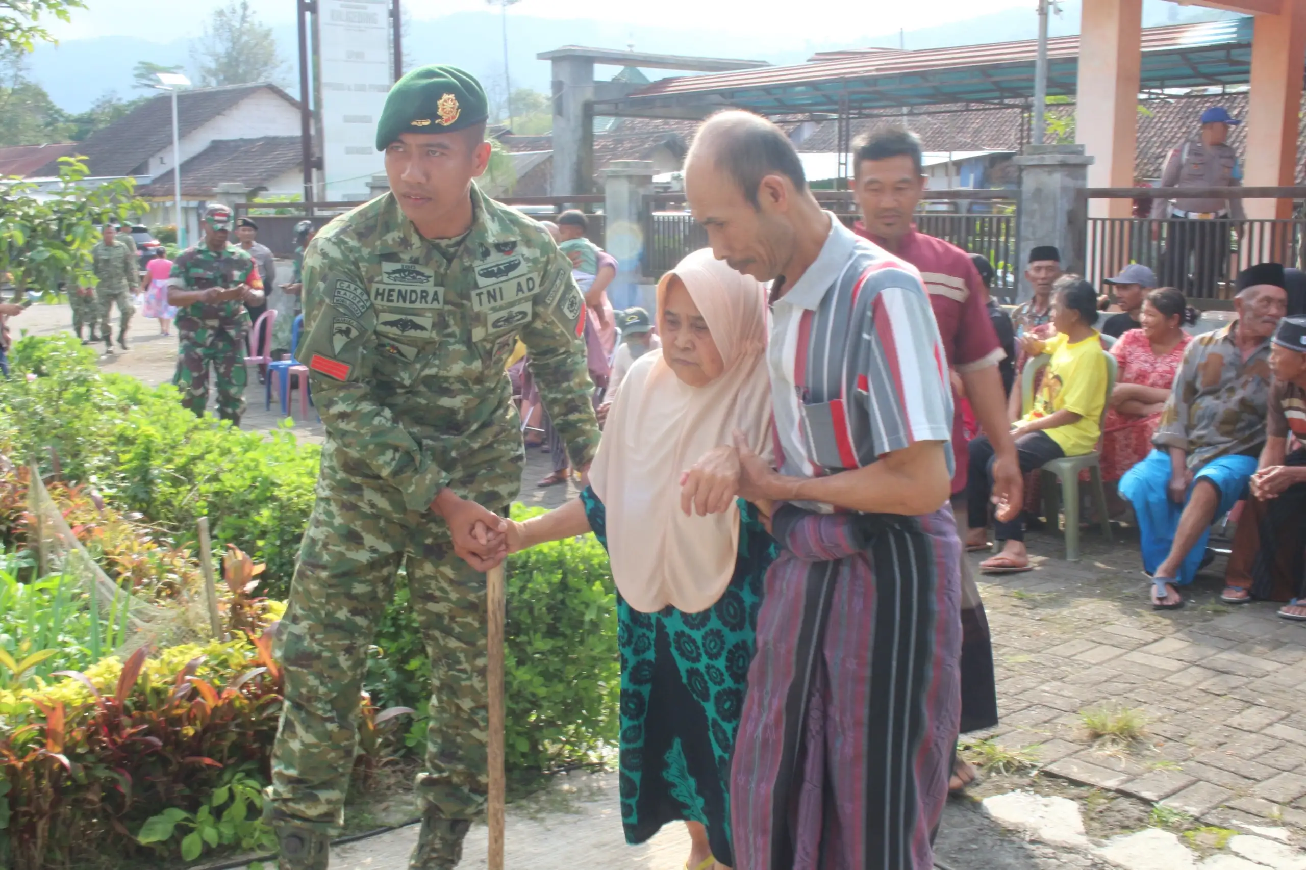 DIPANDU: Anggota TNI membawa lansia yang akan melakukan pemeriksaan kesehatan gratis. (ILHAM/RJ)