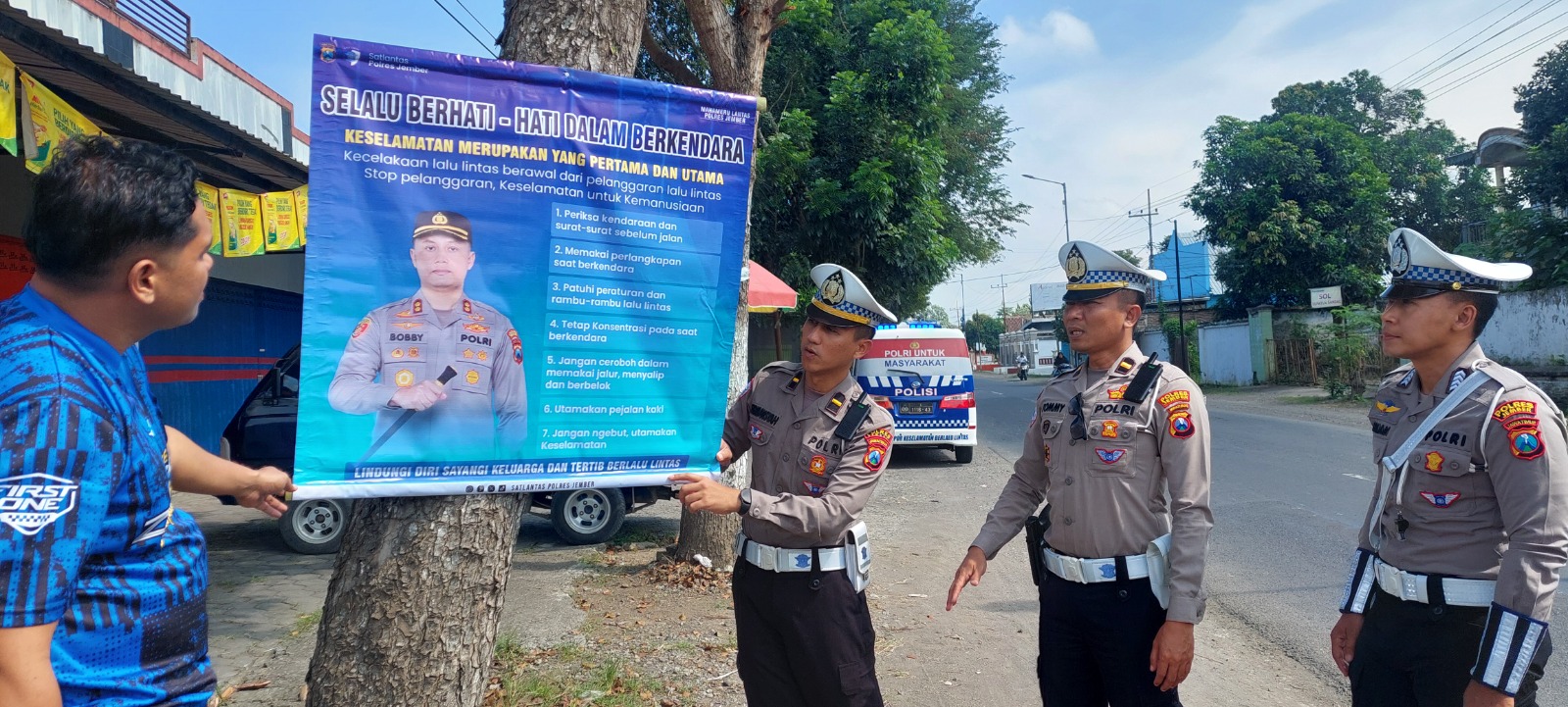 PASANG HIMBAUAN: Pemasangan banner himbauan untuk mengurangi kecelakan di wilayah pinggiran seperti di jalan jurusan Ambulu- Wuluhan Jumat (23/5). (JUMAI/ RADAR JEMBER)