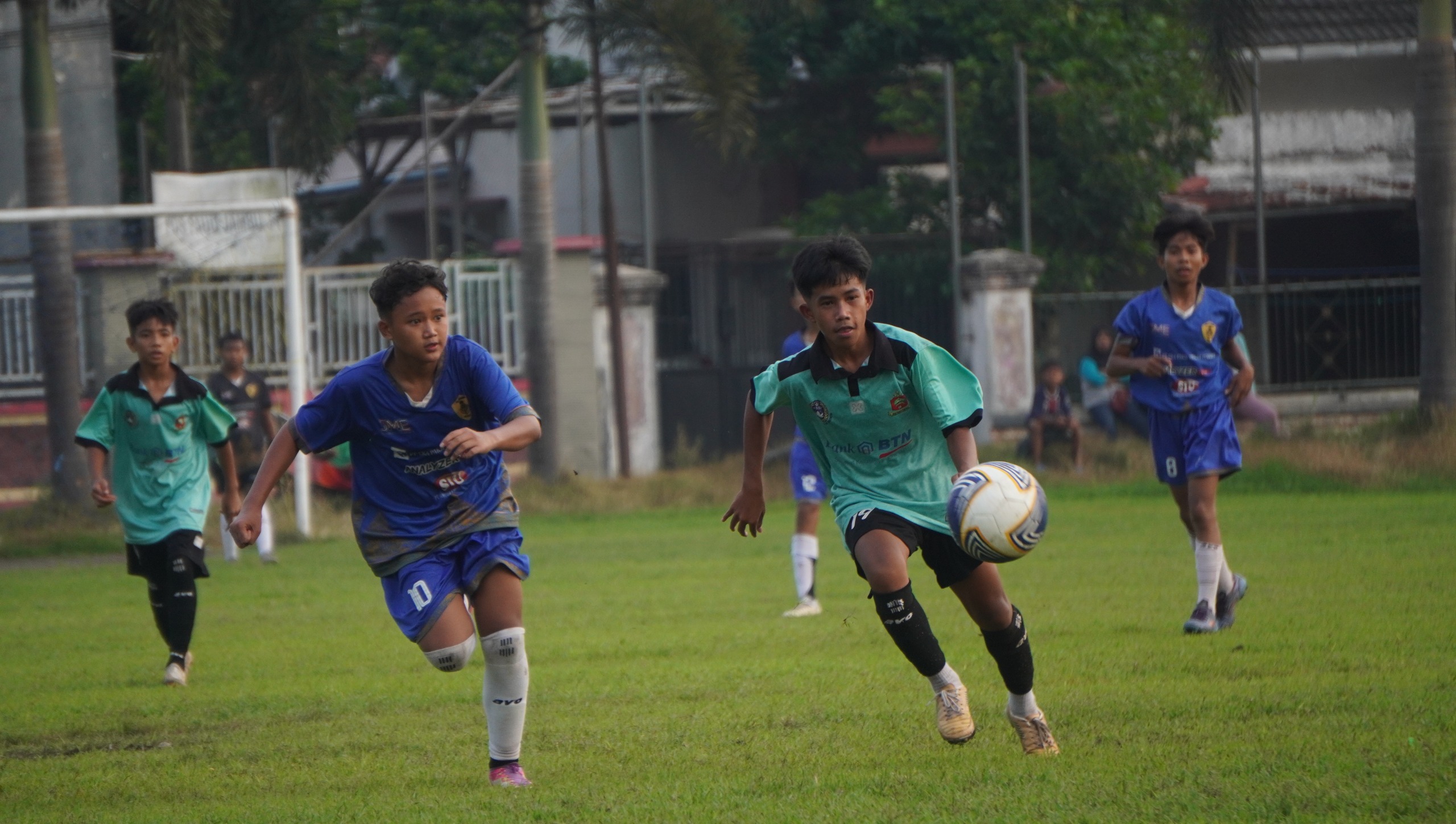 DEMANGAT: Pemain Dharaka Jaguar U15 (Hujau Toska) berusaha mengejar bola kala bertanding melawan SSB Rejo Agung (Biru) (YULIO/RADAR JEMBER)