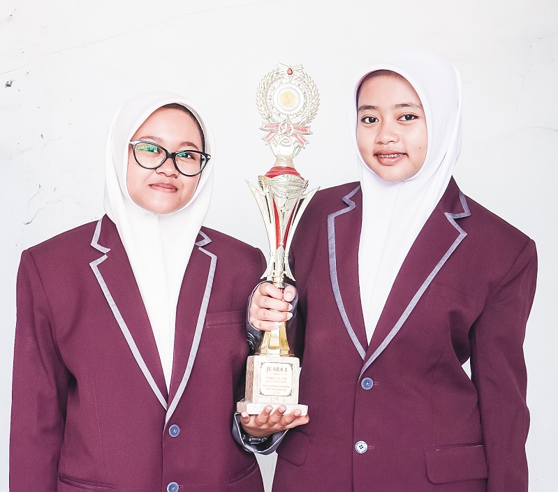 MEMBANGGAKAN: Lovely Aulia Admetta dan Rifqoh Nafi&rsquo;ah, siswa kelas XI IPS 2 SMA Nuris Jember, berhasil meraih predikat Esai Terfavorit dalam ajang National Essay Olympiad 2025. (NURIS JEMBER)