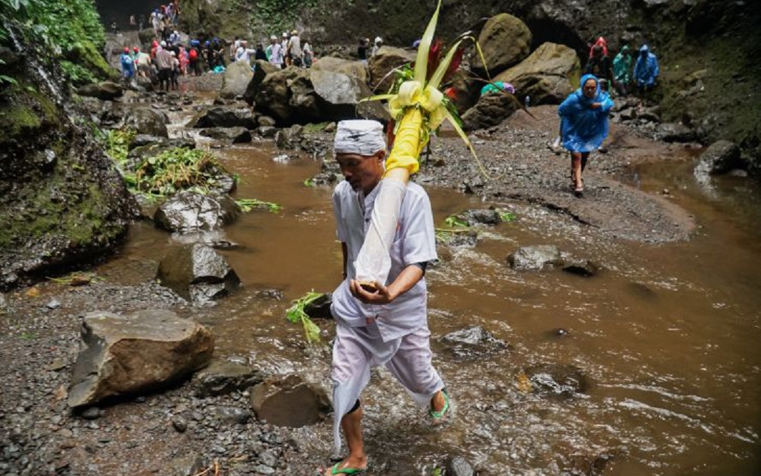 Pemangku adat masyarakat Suku Tengger membawa air suci dalam wadah bambu saat ritual Mendak Tirta di Air Terjun Madakaripura, Kabupaten Probolinggo, Jawa Timur, Minggu (8/6/2025). (Antara)