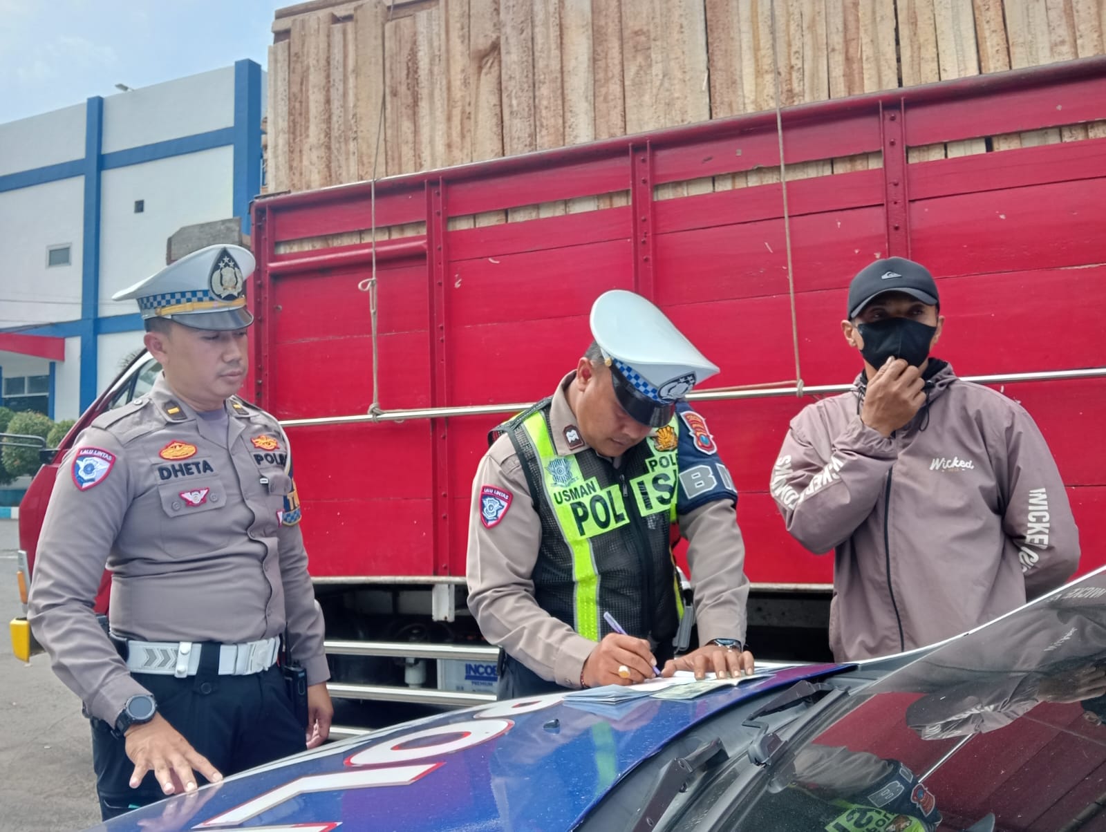 TILANG: Petugas polisi saat menindak truk muatan kayu oleng di jalan raya Sumbersuko, tadi pagi