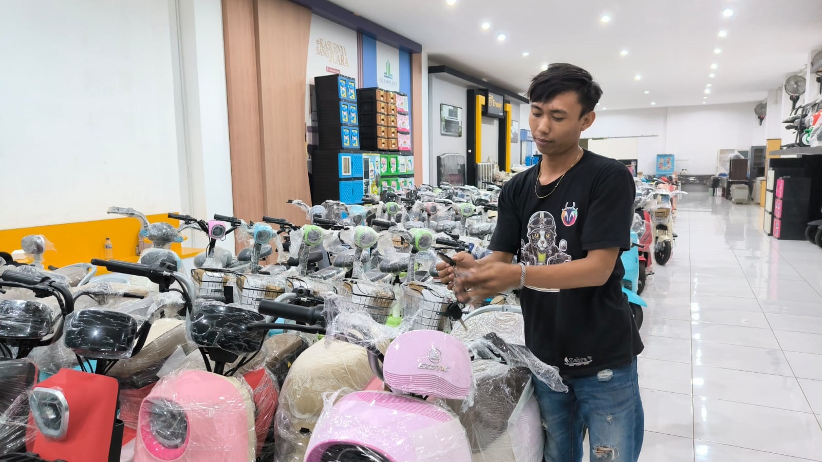 STOK BANYAK: Debi Dwi Novan menunjukkan produk sepeda motor listrik di dealer Masa Premium, Jalan A Yani, Kelurahan Kepatihan, Kaliwates. (MEGA SILVIA/RADAR JEMBER)