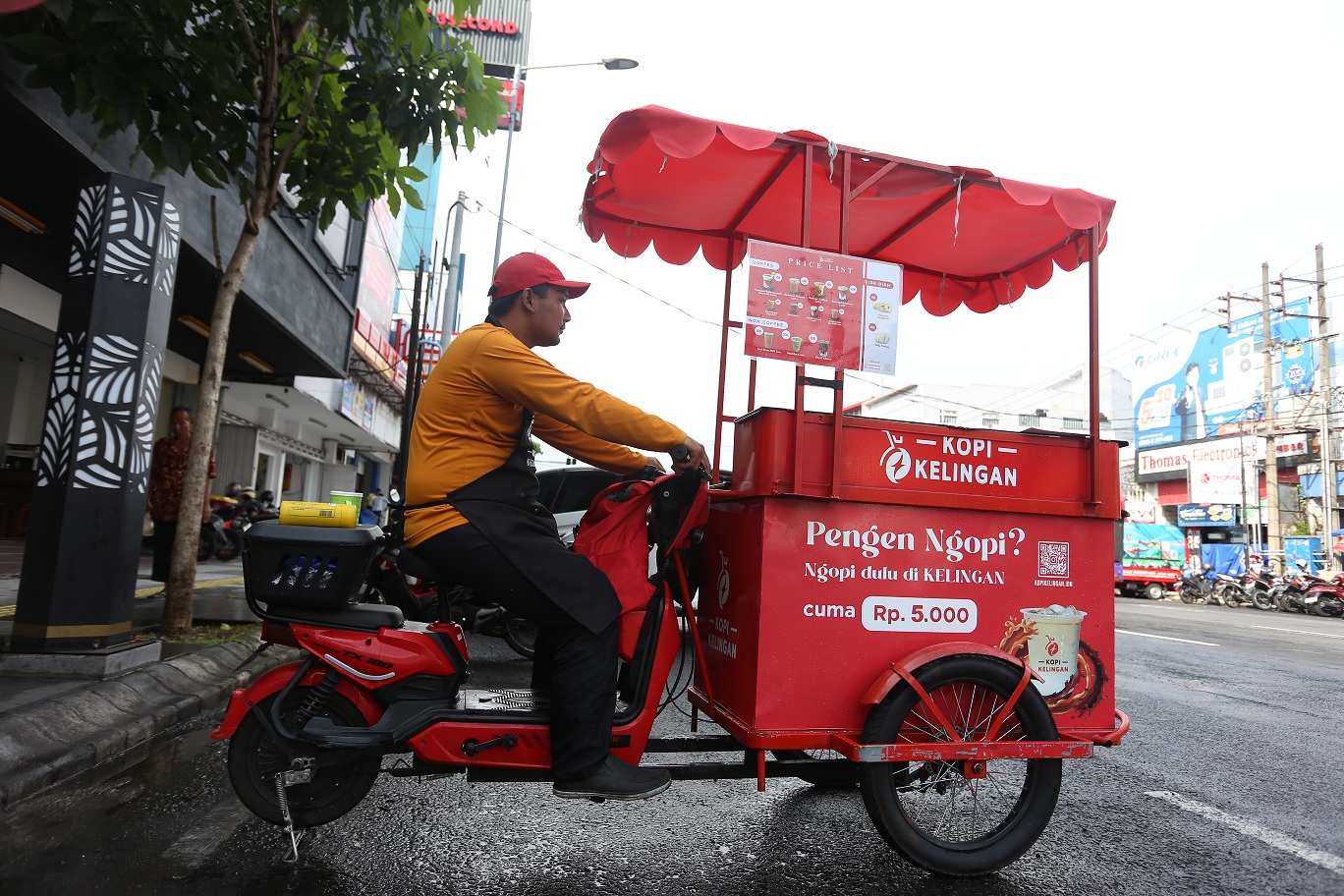 MOBILITAS TINGGI: Anas Robit memarkir sepeda listriknya untuk berjualan kopi keliling di Jalan Gajah Mada, kemarin (15/6/2025).