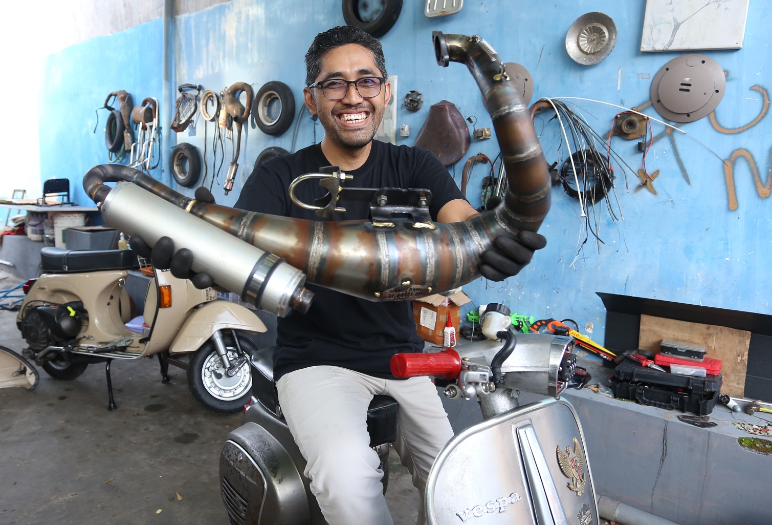 KREATIF: Pendiri Smallframejember, Agus Sakti, menunjukkan knalpot vespa modifikasi buatan tangannya.