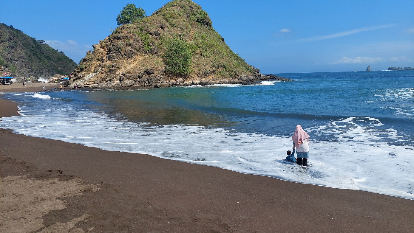 MENEMANI ANAK: Seorang ibu menemani anaknya di pinggir pantai meskipun kondisi ombak besar, Jumat (27/6/2025).