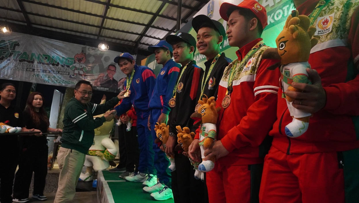 TERIMA MEDALI: Ketua KONI Jember Sutikno memberikan medali emas ke atlet biliar Jember Edrick Danu Wijaya dan Trading Juwarenda, Selasa (1/7/2025) di Carabao Pool, Kota Batu.