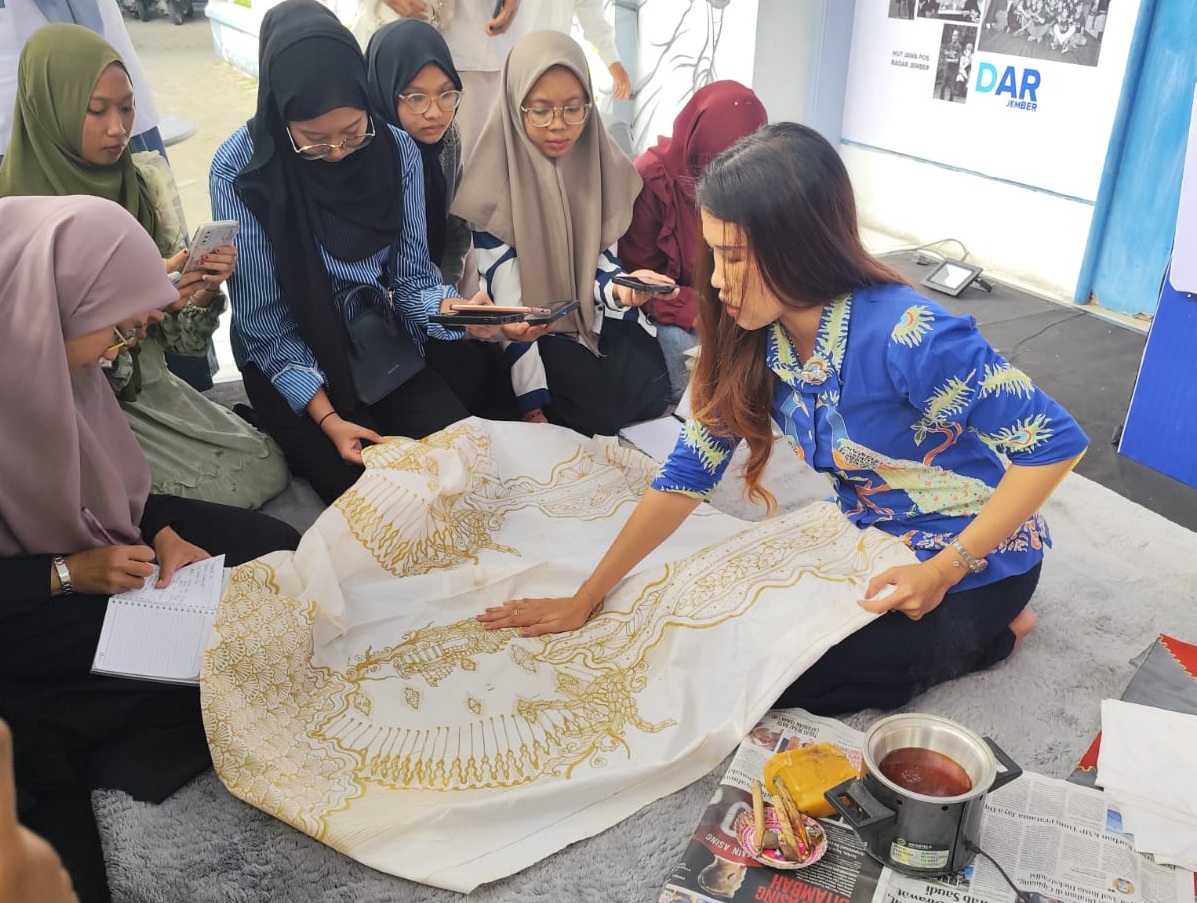 KREATIF: Enno Helga membatik dengan dengan teknik tarikan canting, di depan pintu utama kantor Radar Jember, (16/7/2025) kemarin.