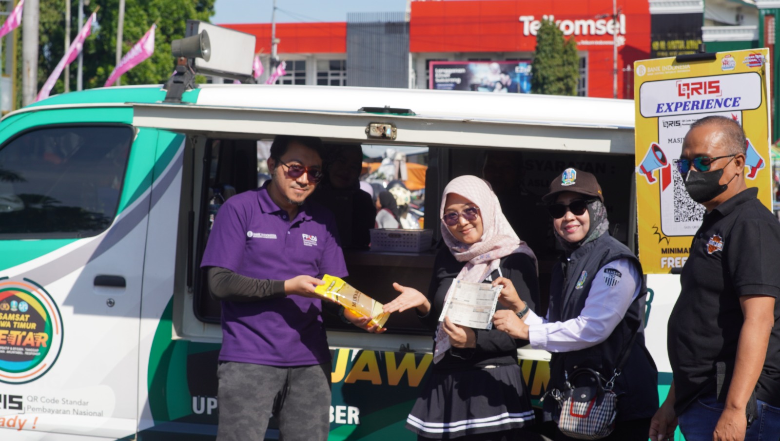 Warga Jember mendapatkan minyak gratis usai membayar pajak menggunakan QRIS saat kegiatan Dulur Sekarkijang KPwBI Jember. (Sidkin/Radar Jember)