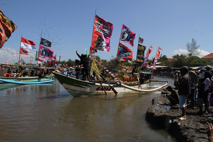 DIARAK: Iring-iringan jukung pembawa sesaji yang siap dilarung saat memasuki pantai Cemara, Dusun&nbsp; Getem, Desa Mojomulyo, Kecamatan Puger pada Minggu (20/7) siang kemarin.