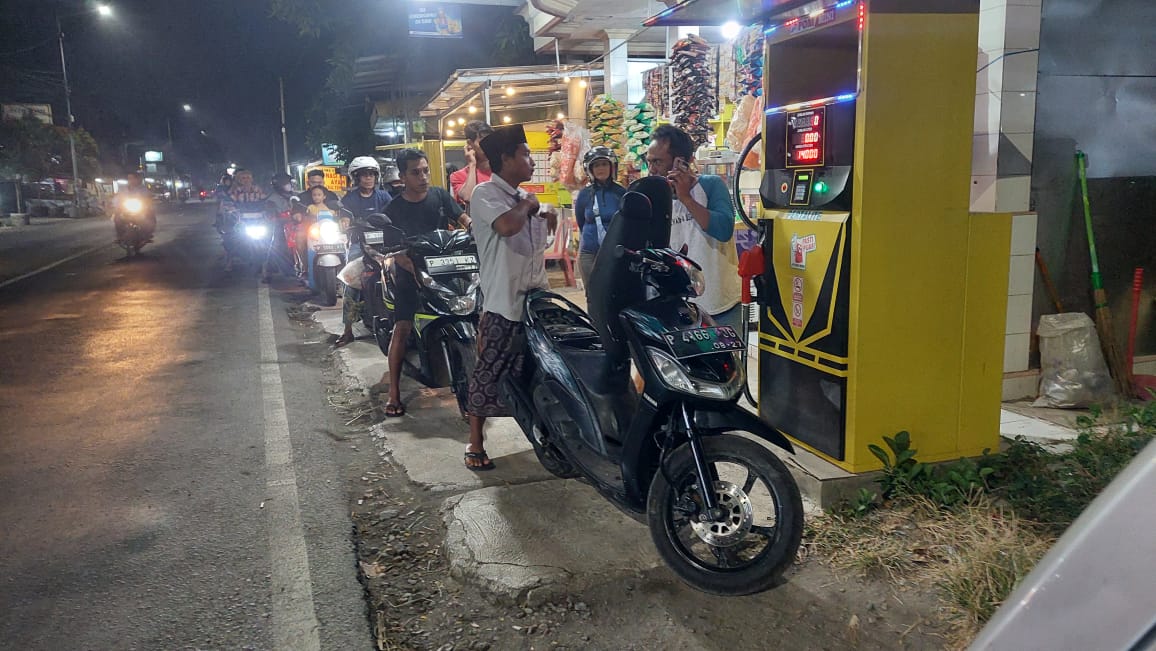 ADA ANTRIAN: Salah satu Pom Mini toko Madura di Jalan MH Thamrin, Desa/ Kecamatan Ajung, Jember juga terjadi antrian pengendara sepeda motor yang membeli bensin eceran pada sabtu (25/7). (JUMAI/RJ)