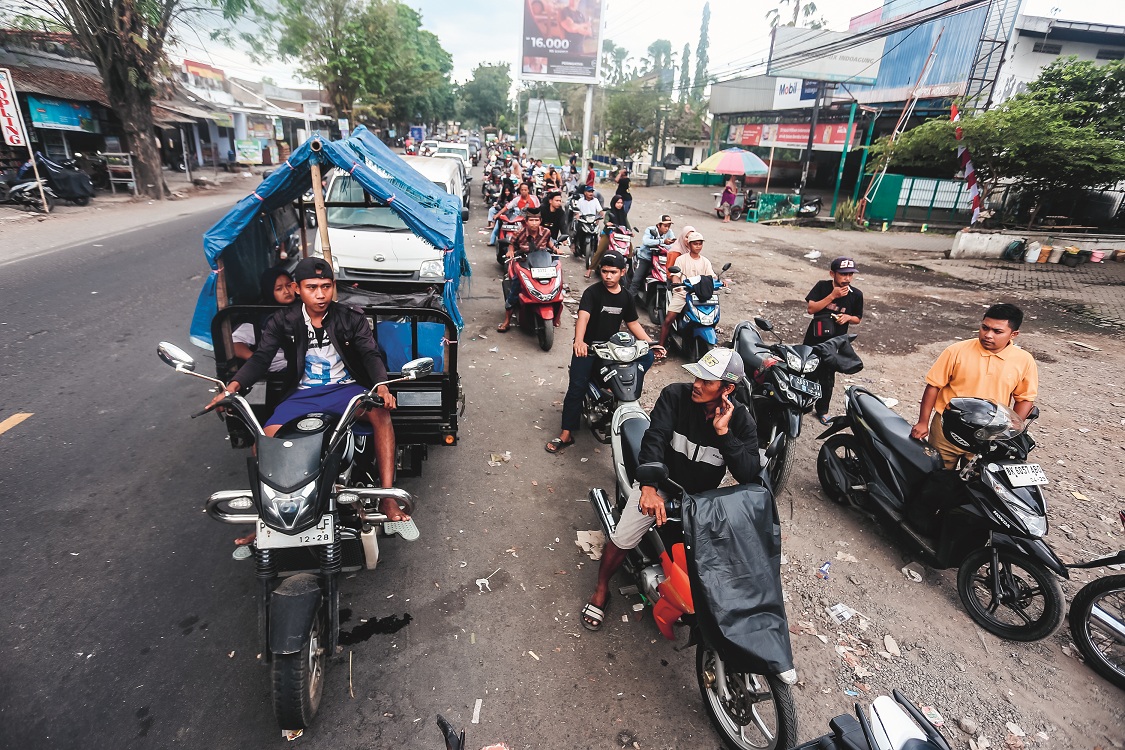 MASIH MENGULAR: Antrean di SPBU Kelurahan Mangli, Kecamatan Kaliwates, masih mengular hingga badan jalan (29/7). Kendati demikian, antrean ini tak sepanjang hari sebelumnya.