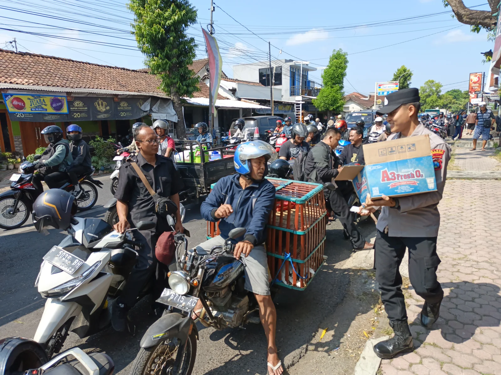 BAGI AIR MINERAL: Petugas kepolisian ketika membagikan air mineral gratis kepada pengendara roda dua yang antre di sekitar SPBU Nangkaan Bondowoso