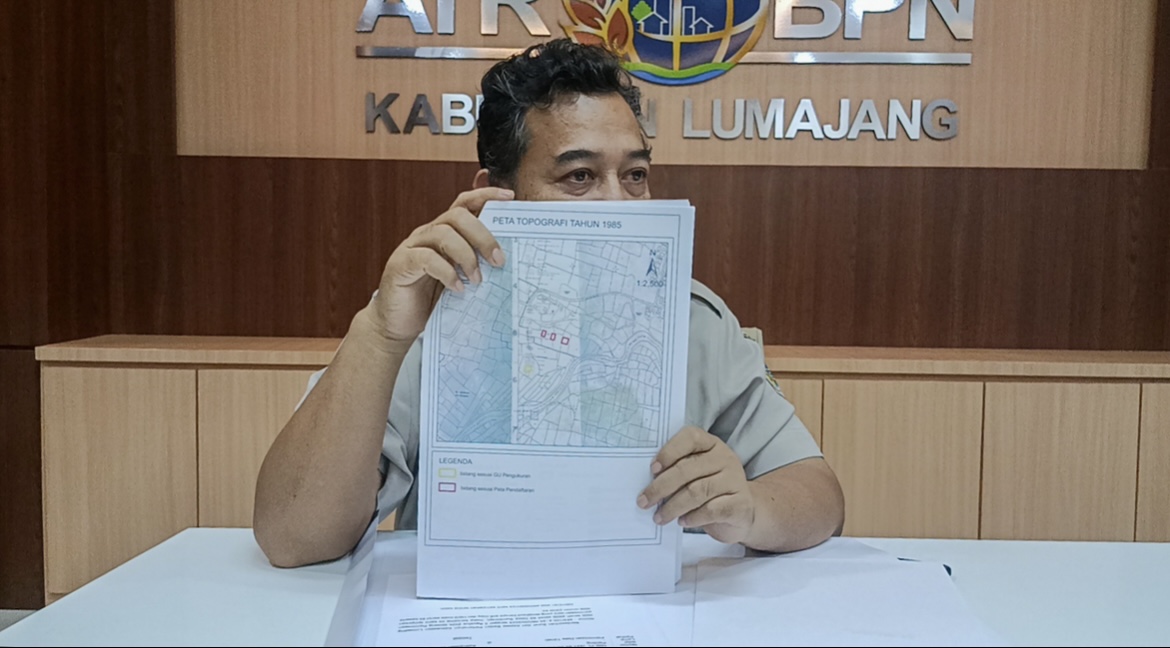 TUNJUKKAN: Kasi Pengendalian Penanganan Sengketa Konflik Perkara BPN Lumajang Tatang Hariyadi saat menunjukkan peta lahan yang dianggap sebagai alihfungsi lahan sungai. (ATIEQSON MAR IQBAL/RAME)