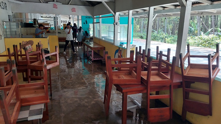 BERSIH-BERSIH: Ibu Shanty, pemilik warung di puncak Gumitir (Watu Gudang) bersihkan sampah daun yang ada di depan warungnya, Senin (1/9).