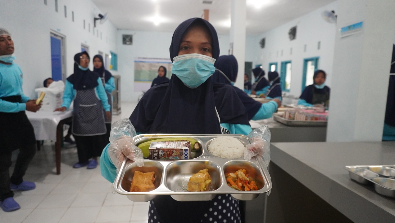 TERUS PRODUKSI: Pegawai dapur Branjangan, Kecamatan Patrang menunjukkan menu MBG. Kini terus berjalan dengan produksi menu berbeda untuk ribuan siswa.