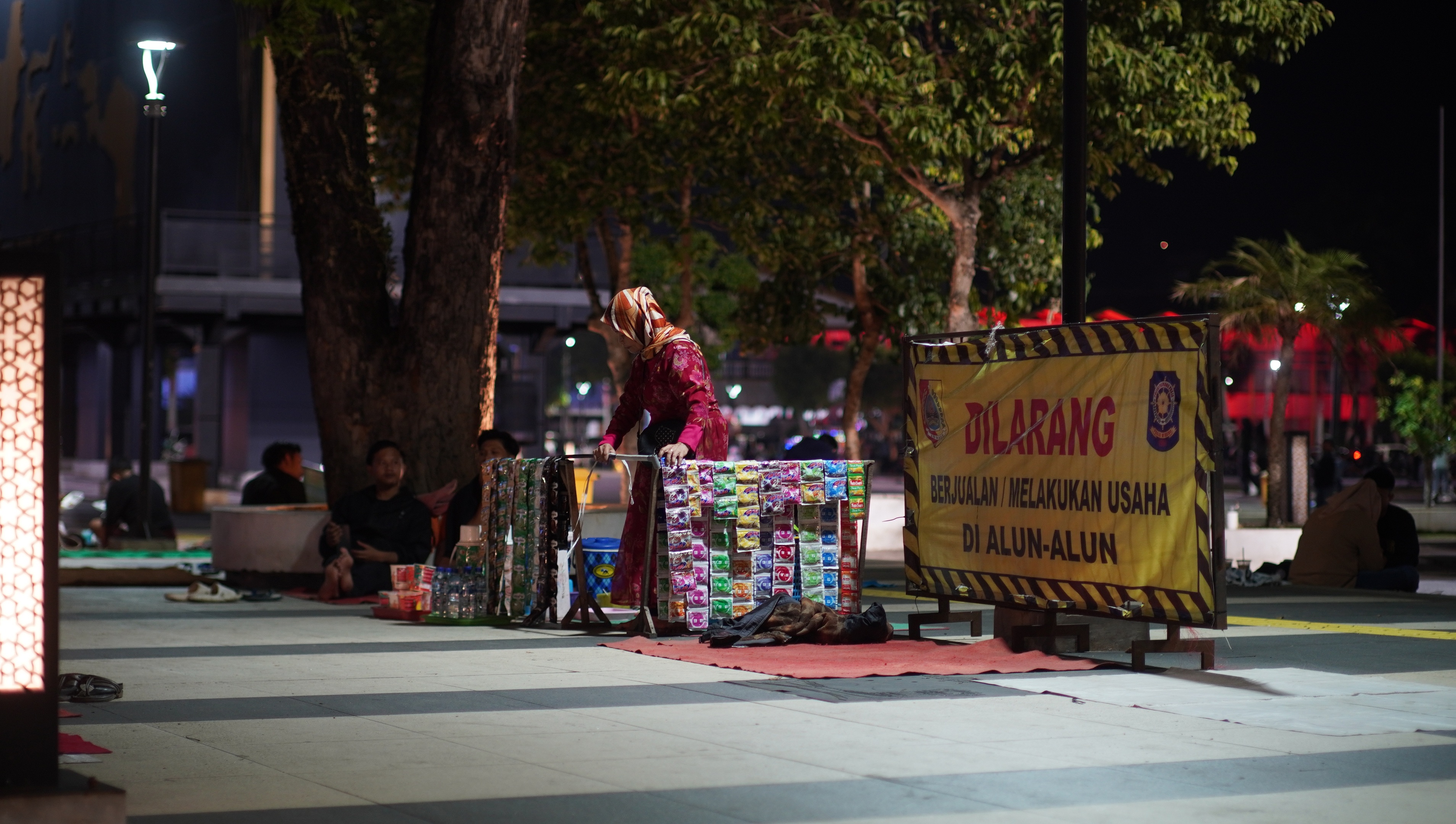 LANGGAR ATURAN: Seorang pedagang kaki lima (PKL) di Alun-Alun Jember menjajakan dagangannya berupa berbagai jenis minuman, tepat di samping himbauan larangan berjualan, Senin malam (8/9).