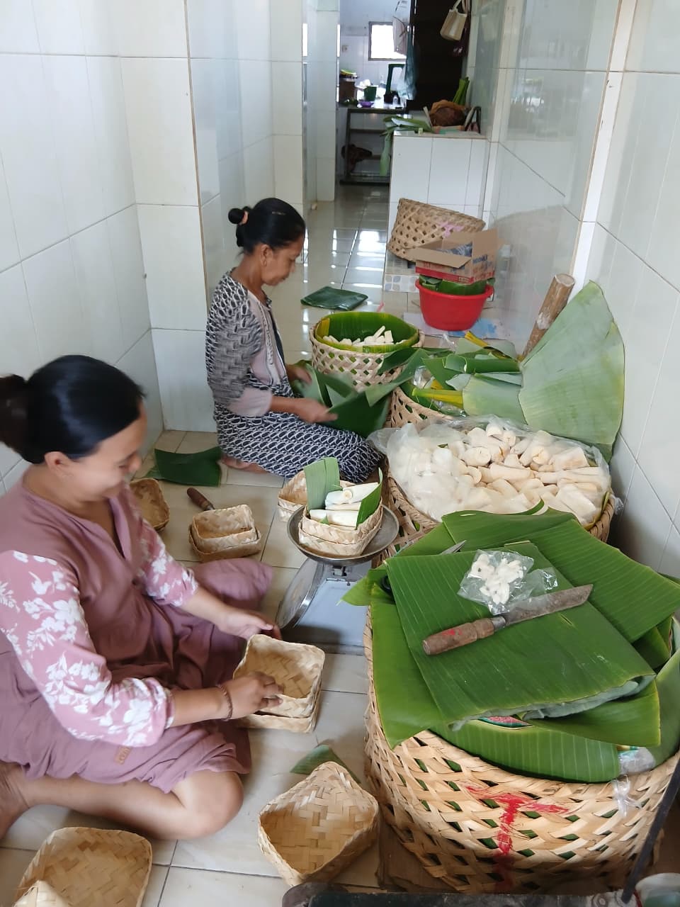 DIKEMAS: Dua orang pekerja rumah produksi Tape, ketika memproses pengemasan tape tradisional dengan daun pisang sebelum dipasarkan.(AFFAN KURNIAWAN)