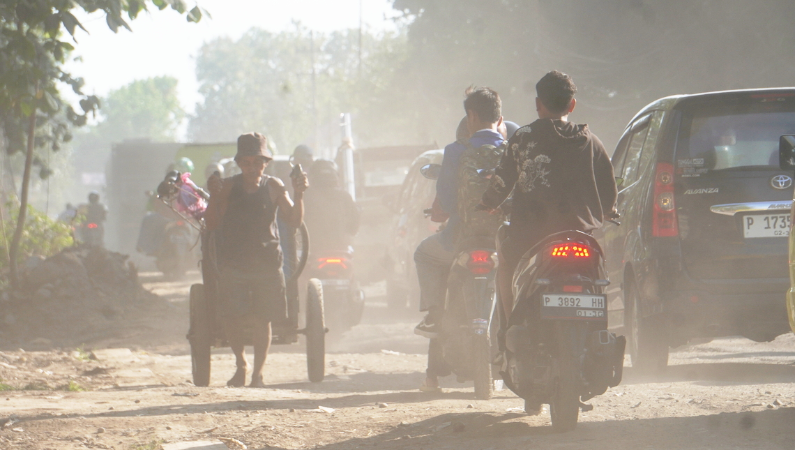 DEBU PEKAT: Para pengendara yang melintasi jalan Rambipuji-Balung harus ekstra sabar karena harus berjibaku dengan debu. Di lokasi, antrean panjang juga sering terjadi karena ada perbaikan jalan.