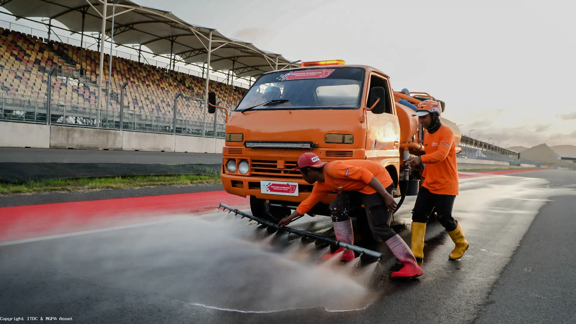 Truk pendukung berwarna oranye yang bertugas menyemprotkan air bertekanan tinggi untuk mengangkat partikel debu ke luar lintasan.