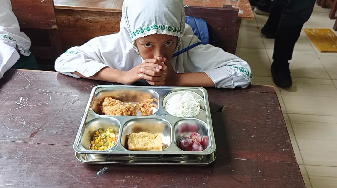 Salah satu siswa di sebuah sekolah dasar swasta di Desa Wonoasri, Kecamatan Tempurejo, Jember, sesaat sebelum menyantap menu MBG (29/9). (Foto: Maulana/Radar Jember)