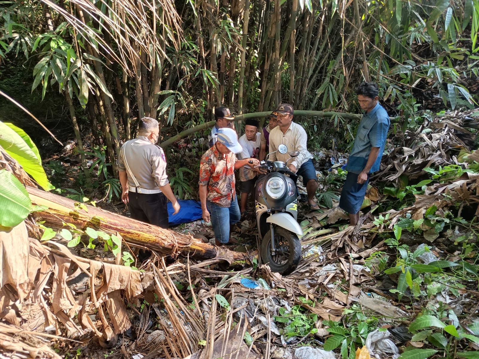 EVAKUASI: Warga sekitar dan pihak kepolisian saat mengamankan motor korban yang jatuh di tumpukan sampah, kemarin.(POLRES LUMAJANG FOR RAME)