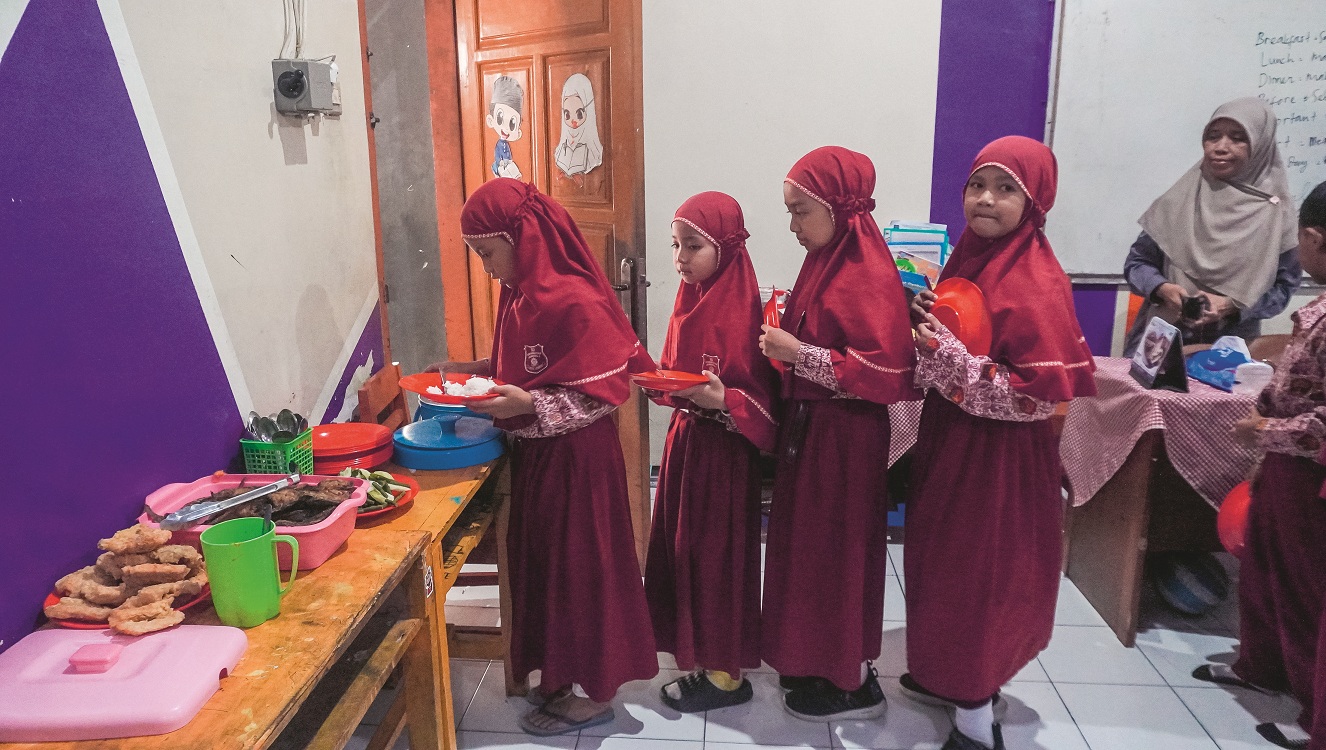 TERTIB: Siswa SD Muhammadiyah 1 Jember mengantre untuk mengambil makan siang, di ruang kelas kemarin.