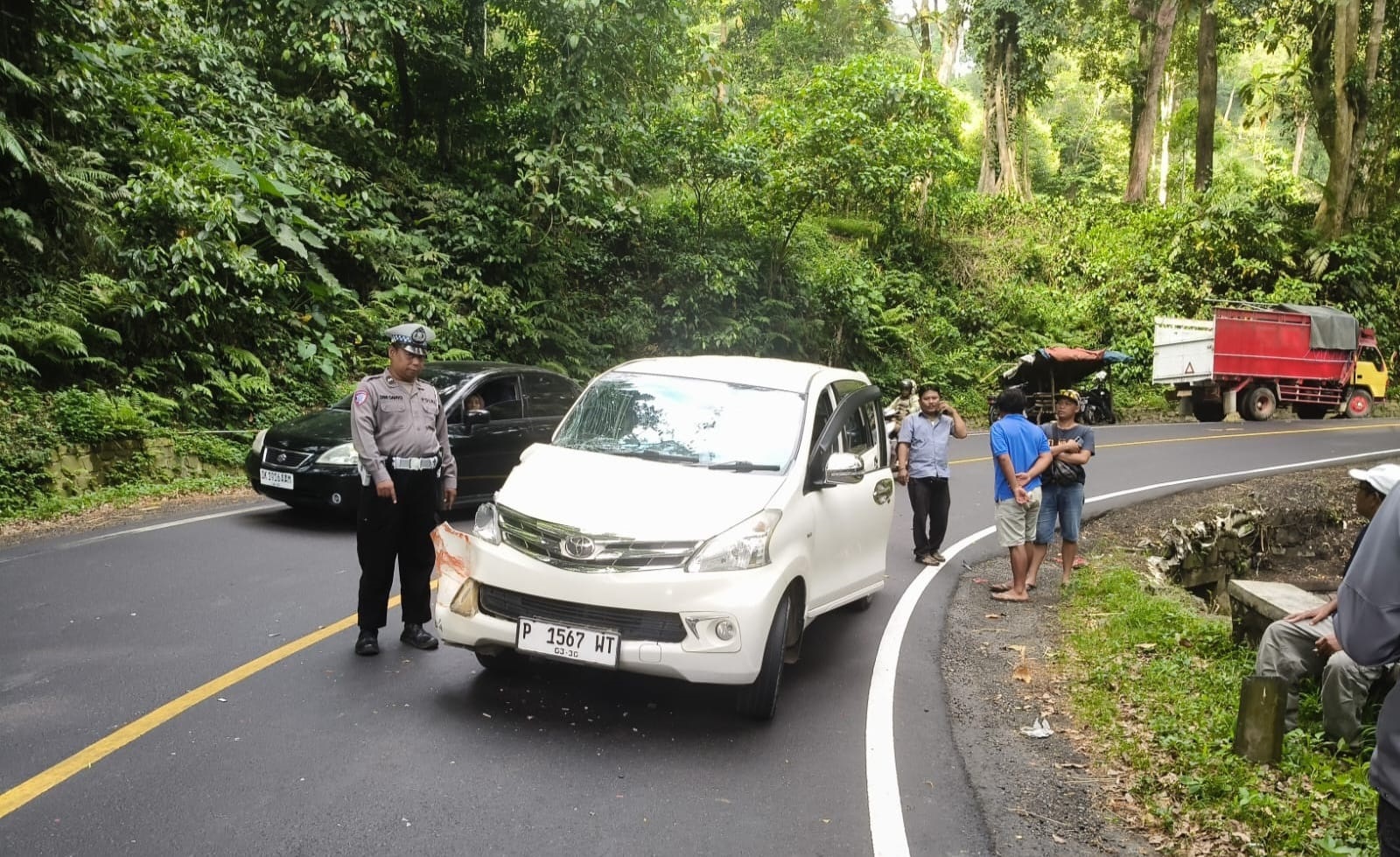 DATANGI LOKASI: Kanitlantas Polsek Silo Aipda Dwi Cahyo mendatangi TKP kecelakaan truk dengan Toyota Avanza, di jalur Gumitir, Desa Sidomulyo, Kecamatan Silo.