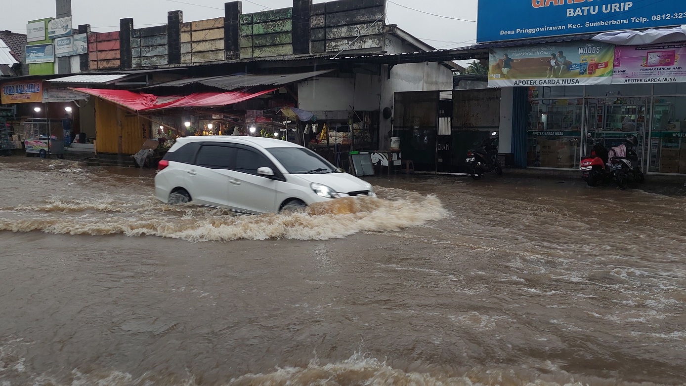 NEKAT: Sebuah mobil menerobos genangan air di Jalan Raya Provinsi jurusan Jember-Lumajan, di Desa Pringgowirawan, Kecamatan Sumberbaru, Rabu (22/10).