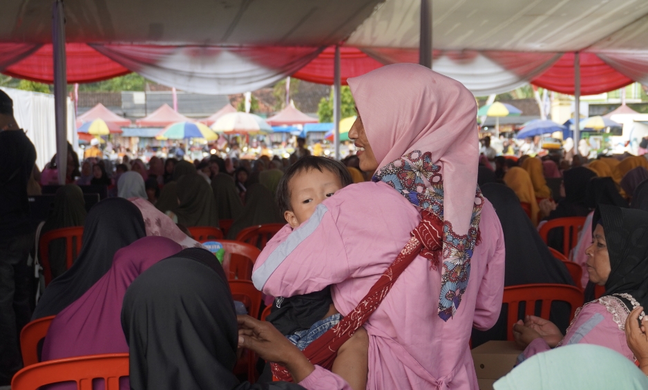 Seorang ibu-ibu di Jember tengah menggendong anaknya. (Foto. Maulana/Radar Jember)