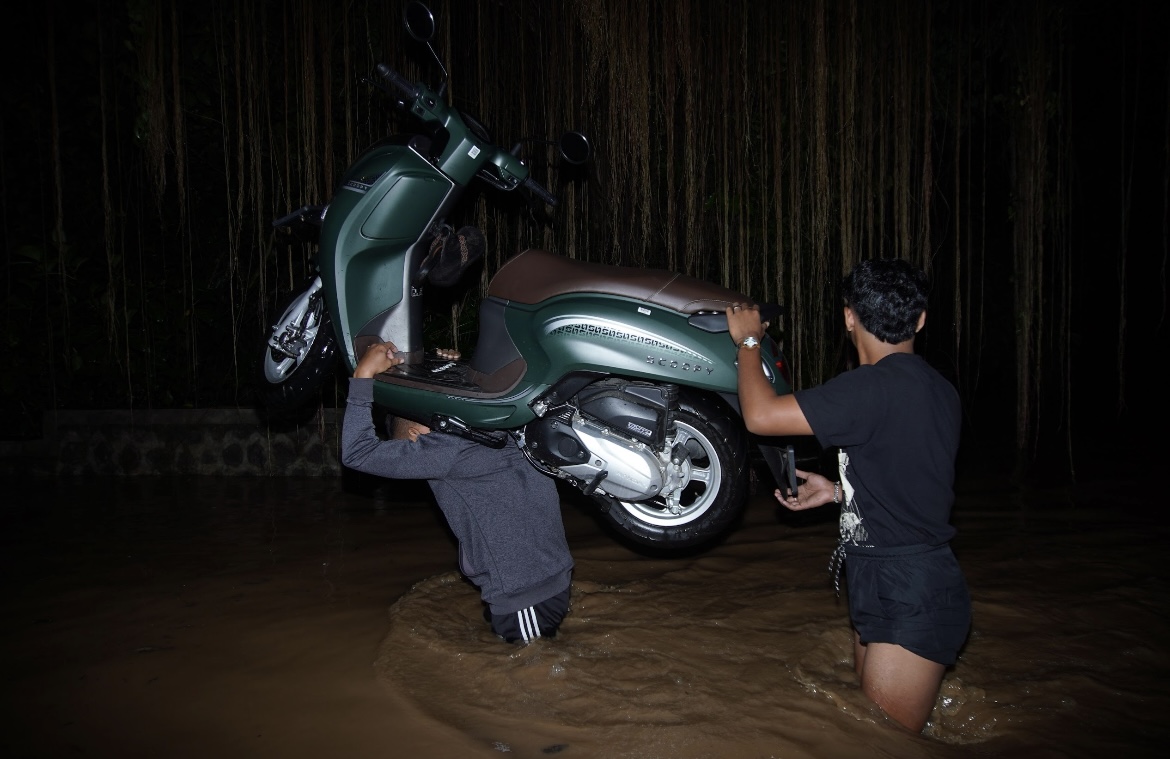 GENDONG: Salah satu warga saat menggendong sepeda motor menyeberangi banjir di Desa Kutorenon, Kecamatan Sukodono.(ATIEQSON MAR IQBAL/RAME)