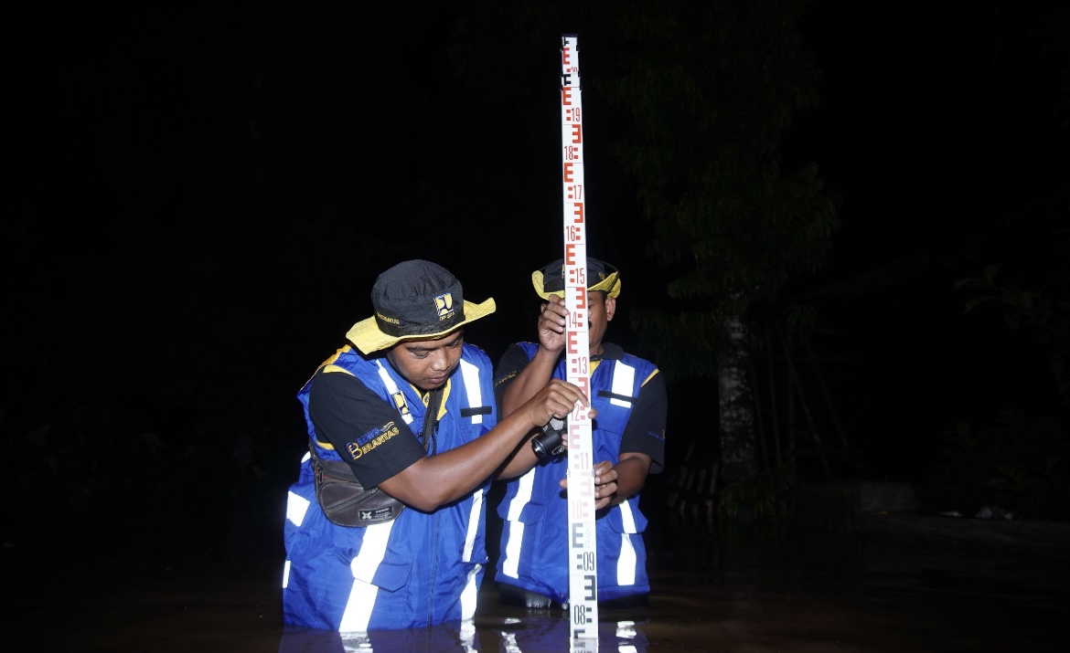 UKUR: Petugas Balai Besar Wilayah Sungai (BBWS) Brantas saat mengukur ketinggian bencana banjir genangan di Desa Kutorenon, kemarin.(ATIEQSON MAR IQBAL/RAME)