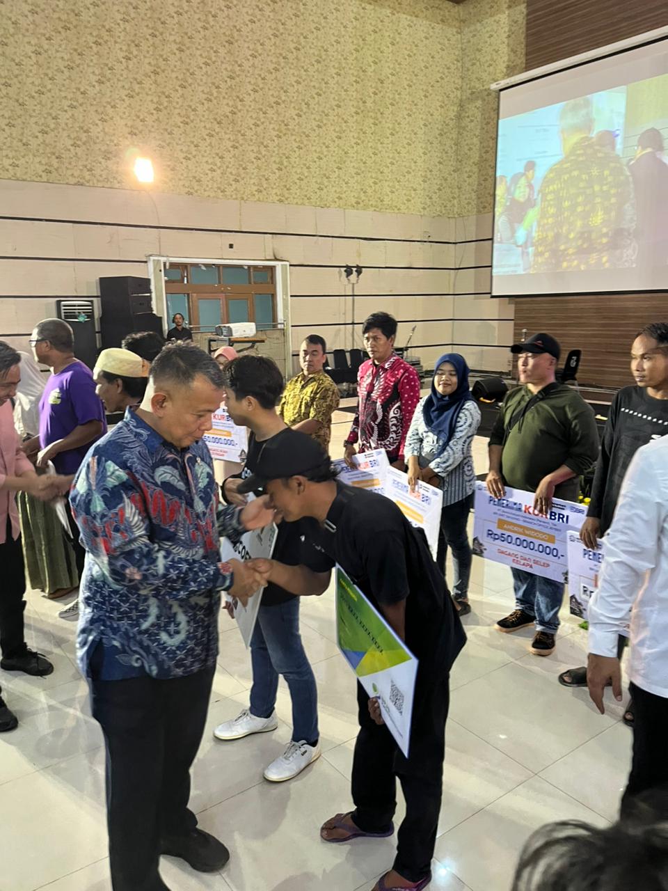 SEREMONIAL: Kepala Kantor BPJS Ketenagakerjaan Cabang Jember Dadang Komarudin memberikan kartu kepesertaan BPJS Ketenagakerjaan pada peserta Kumitra, di Balai Serbaguna, Senin (3/11).