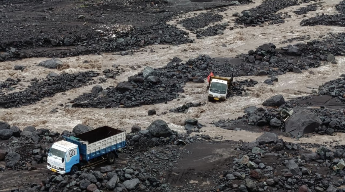 TERJEBAK: Kondisi dua truk milik penambang pasir di Kecamatan Candipuro saat terjebak di aliran lahar Gunung Semeru, kemarin.(ADE APRYANIS/RAME)