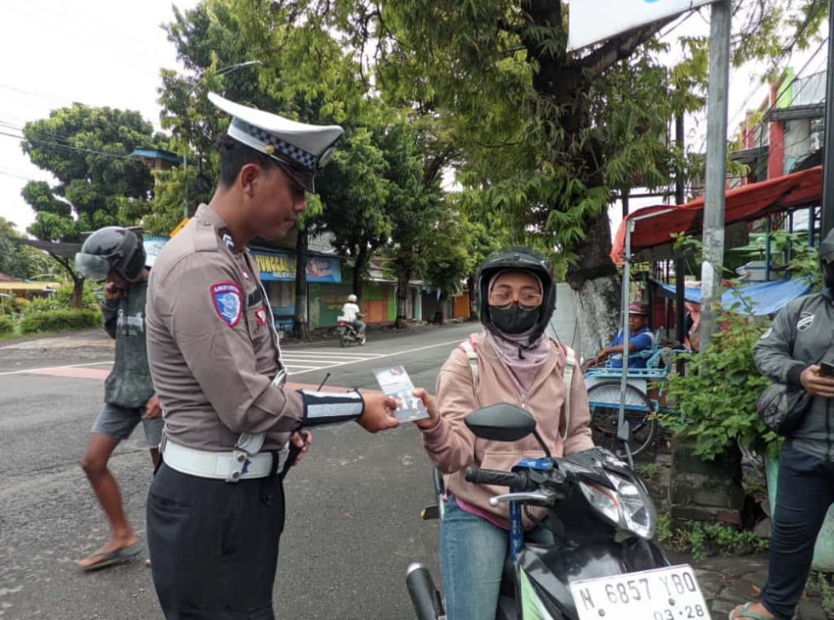 PERINGATKAN: Petugas Satuan Lalu Lintas Polres Lumajang memberikan brosur imbauan tata tertib berkendara untuk antisipasi kecelakaan. (ADE APRYANIS/RAME)