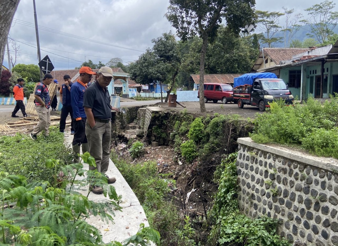 MENGECEK: Petugas saat memantau alat EWS di aliran sungai rawan banjir.(BPBD BONDOWOSO)