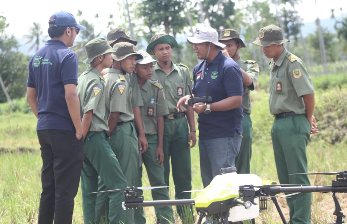 FOKUS: Sejumlah siswa dan petani mendengarkan penjelasan dari pilot drone sprayer di sawah milik warga Sumber Wringin.(ILHAM WAHYUDI/RADAR IJEN)