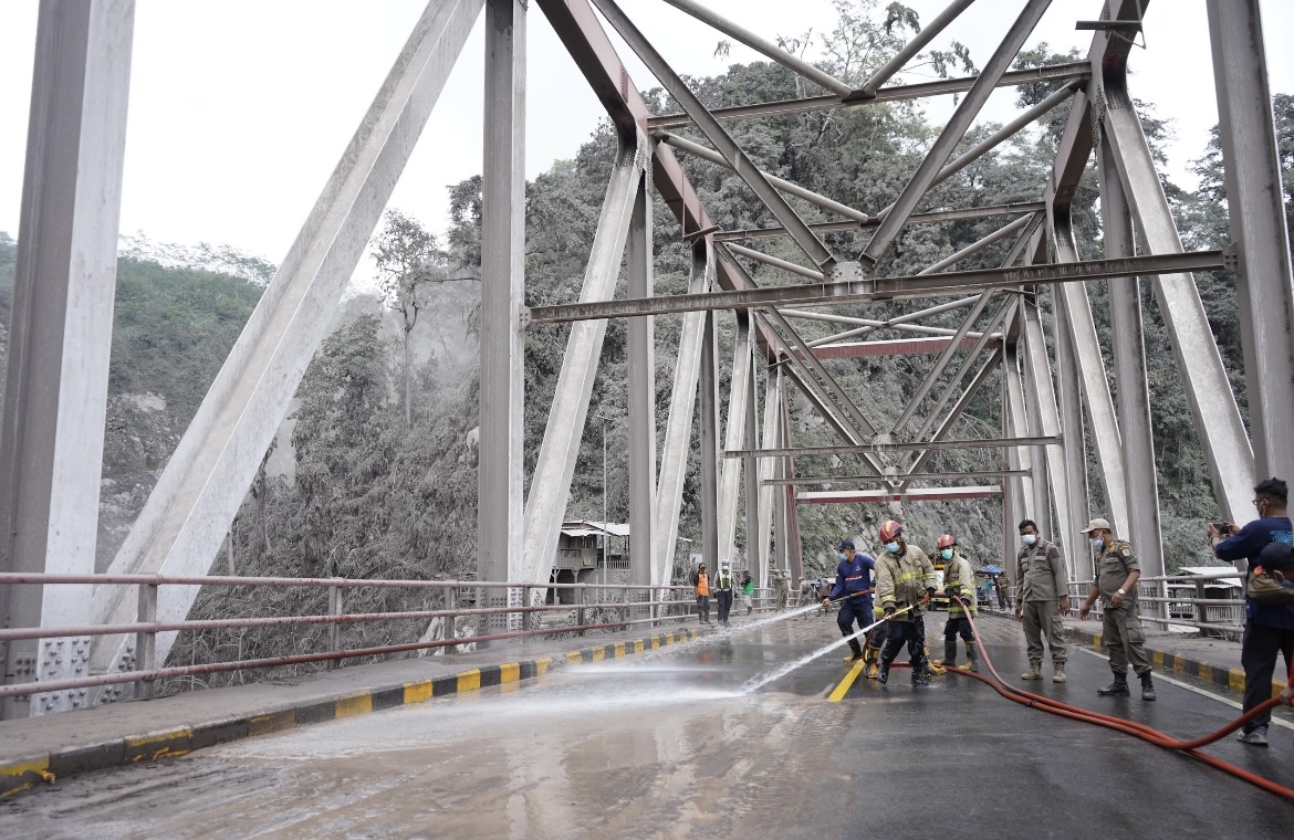 DISEMPROT: Petugas Damkar Lumajang saat membersihkan abu sisa erupsi di Gladak Perak, Candipuro, kemarin.(ADE APRRYANIS/RAME)