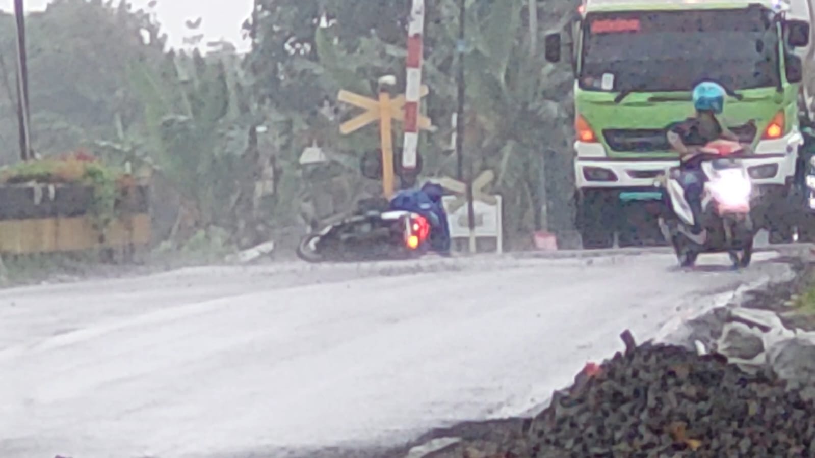 TERJATUH: Pengendara sepeda motor Honda Vario yang terjatuh saat melintas di lintasan rel KA Pecoro, Desa Pecoro, Kecamatan Rambipuji, Jember pada Selasa (2/12/2025). (JUMAI/RJ)