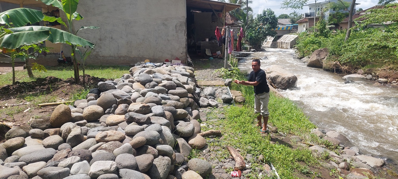 TERDAMPAK LAGI: Haris, warga Dusun Pertelon, Desa Pakis, Kecamatan Panti membuat tanggul yang dikumpulkan dari sungai, karena terdampak banjir susulan.