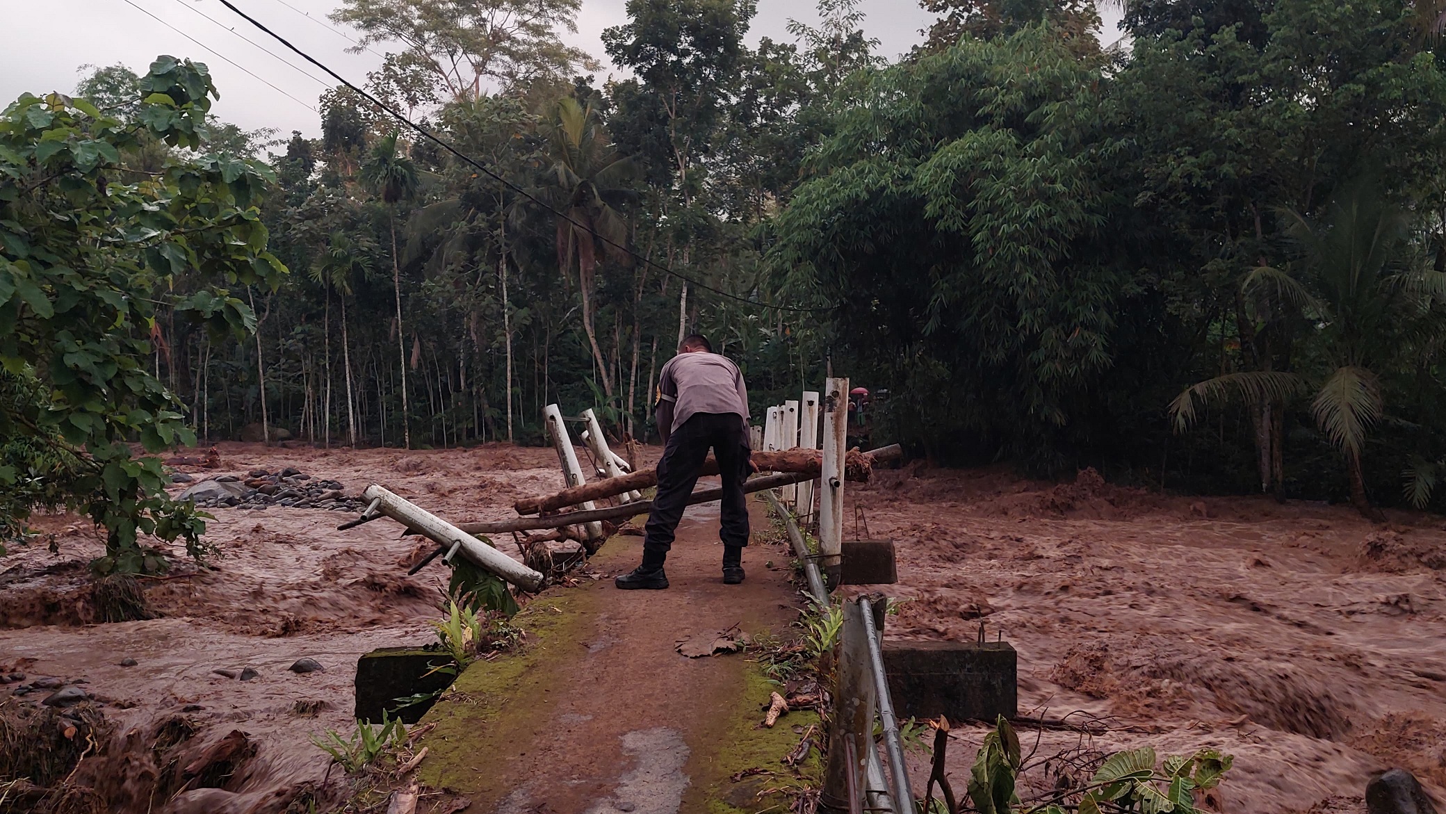 DIPASANG PORTAL: Petugas Polsek Sumberbaru memasang portal dari potongan kayu agar pengendara dilarang melintas saat banjir datang.