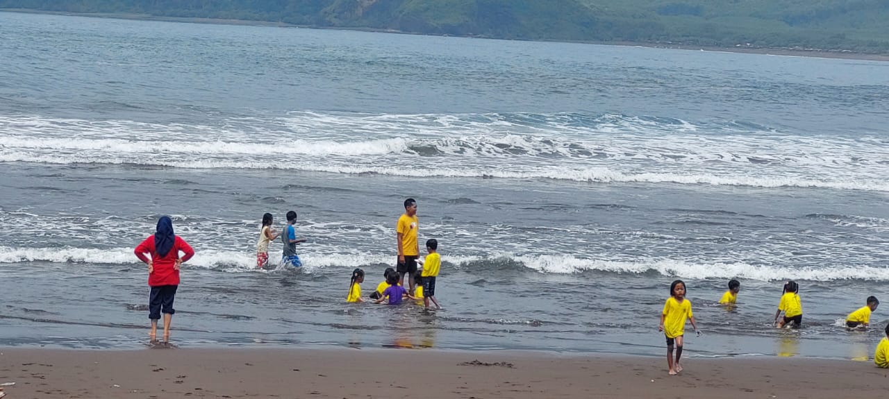 MASIH NEKAT MANDI: Pengunjung pantai Payangan yang masih saja bermain air di tepi pantai hingga ketengah Minggu (14/12/2025)