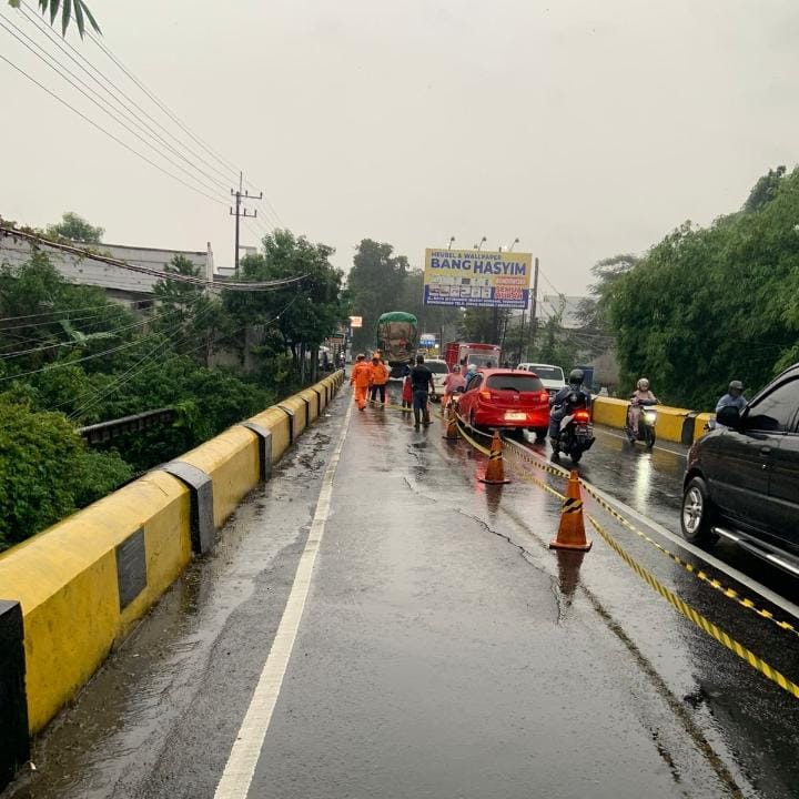 Petugas saat memasang garis pembatas pada ruas jembatan yang retak