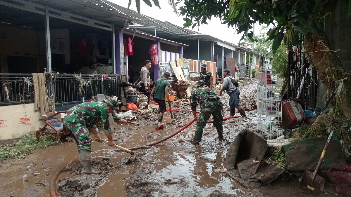 GOTONG ROYONG: Warga bersama personel BPBD, TNI, Polri, dan relawan melakukan pembersihan material sisa banjir di Perumahan Villa Indah Tegal Besar, kemarin (16/12/2025).
